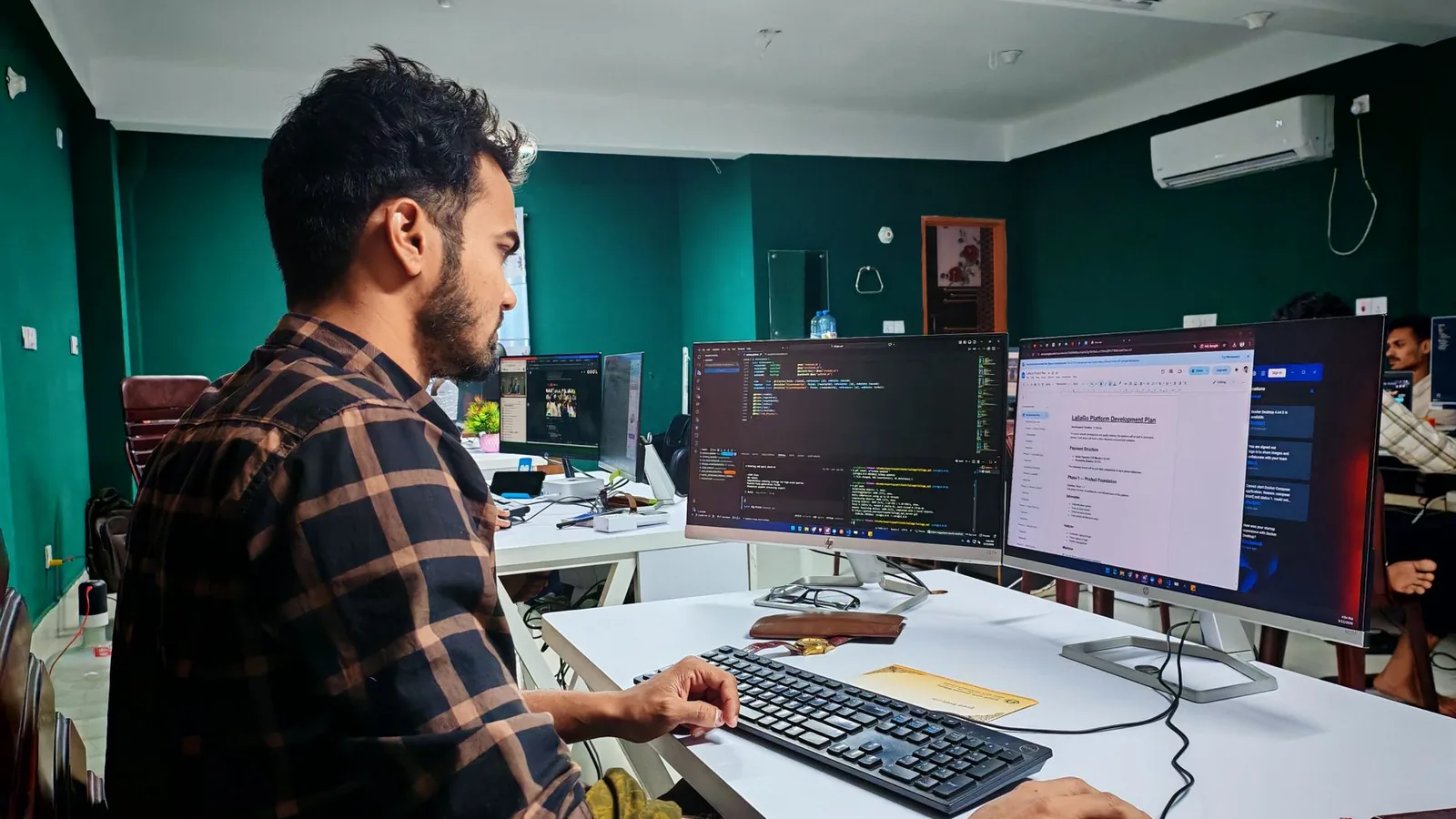 Pessoa programando diante de dois monitores com o editor de código aberto