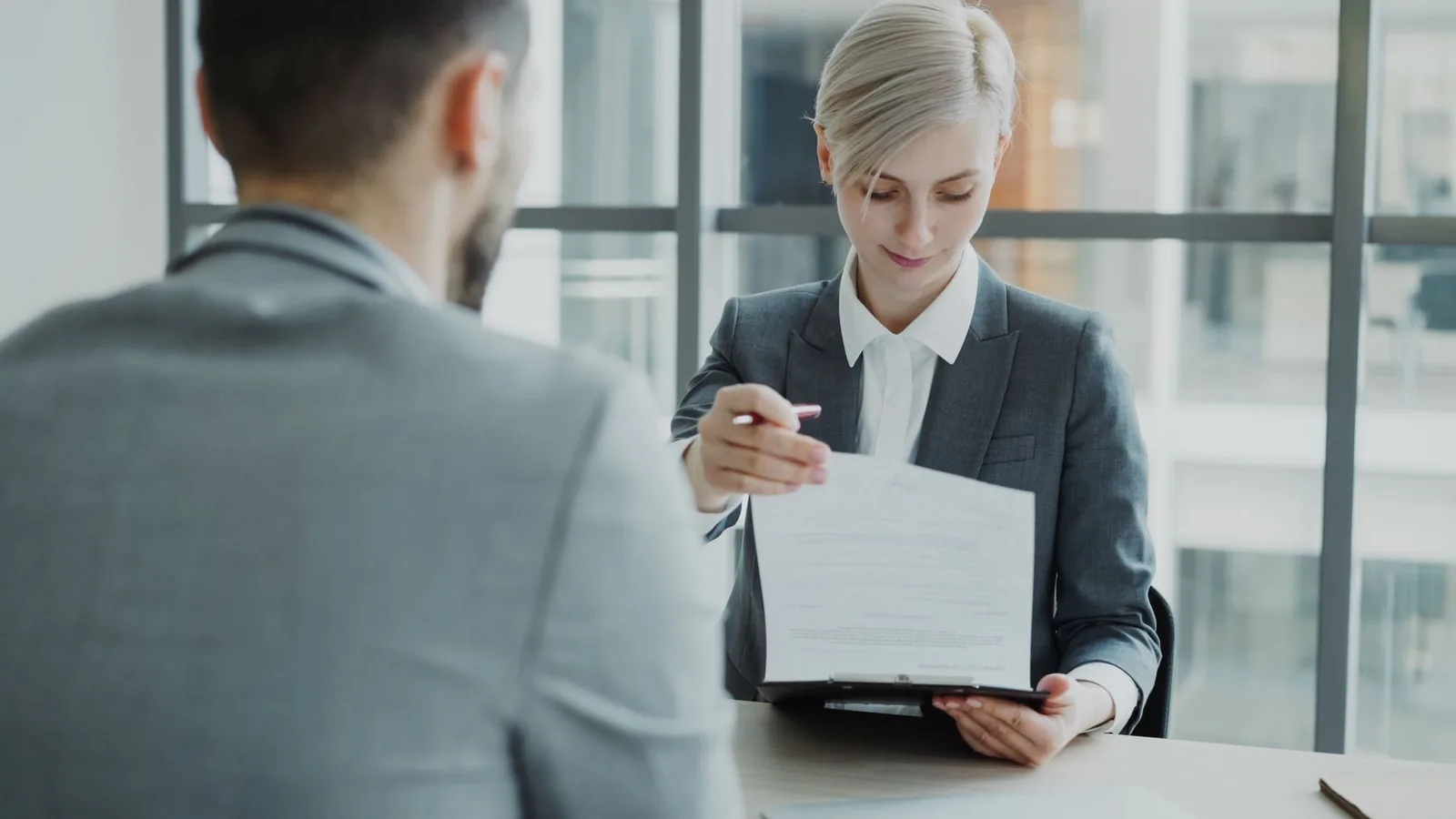 Duas pessoas revisando o documento da proposta sobre a mesa, num escritório claro